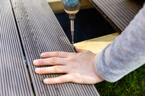 terrace deck construction - man installing wpc composite decking boards