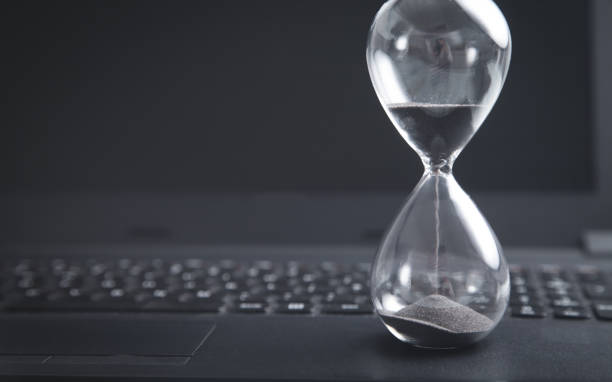 istock Hourglass on laptop keyboard. Time. Business 1221951425