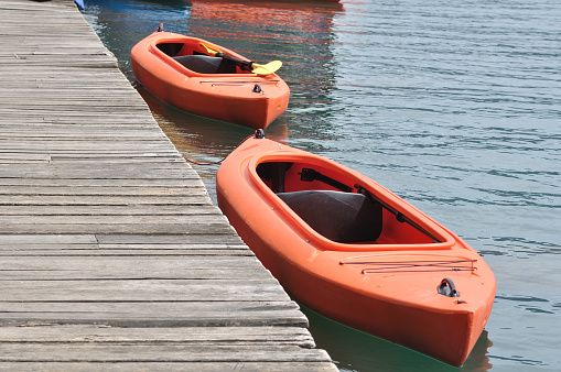 Two orange kayak beside wooden dock