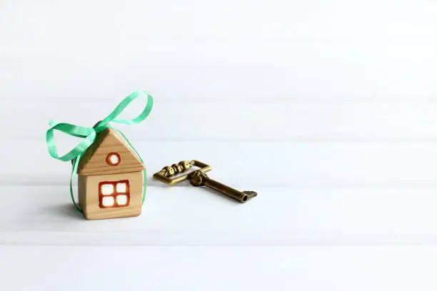 house with a green bow and golden key on a light background with copy space