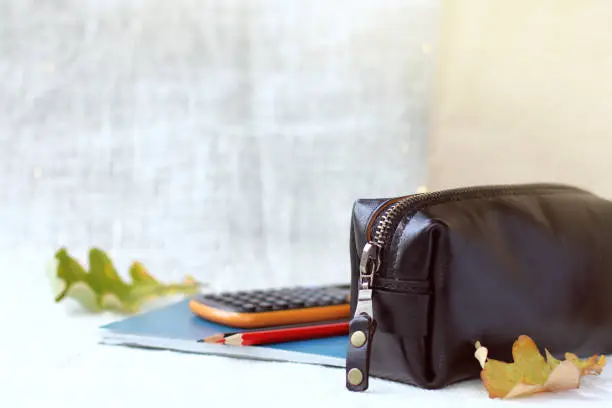 large leather pencil case with lock against the background of calculator with pencils and notebook