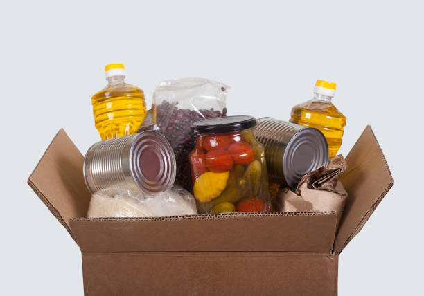 シリアル、米、植物油、豆類、缶詰の野菜の製品セットを、明るい背景に取り入れた箱。助け、慈善団体。社会。寄付。 - oil distribution ストックフォトと画像