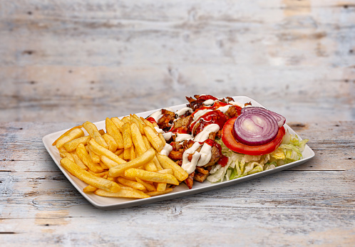 Gyros souvlaki and french fries in white plate on wooden table