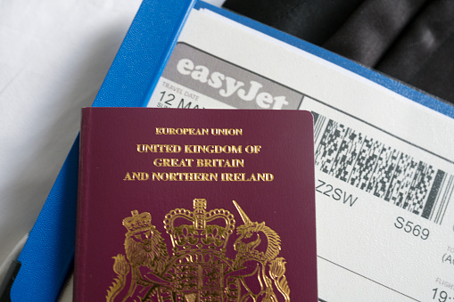 A UK passport on a bed with a boarding card ready for packing for a golf trip. Huntingdon, Cambridgeshire, UK.