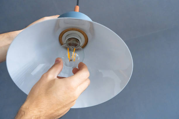 istock Close-up. A hand changes a light bulb in a stylish loft lamp. Spiral filament lamp. Modern interior decor. 1221969297