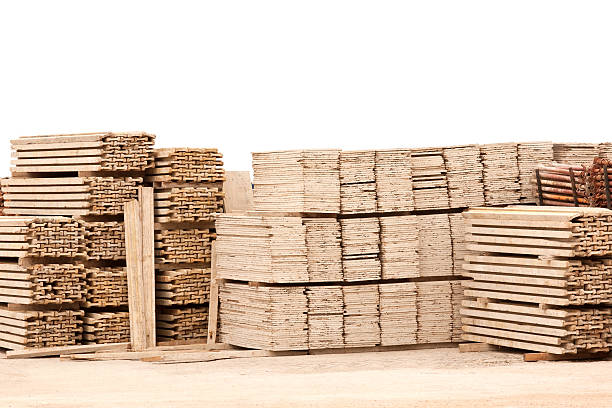 Pile of wooden planks in gravel ground against white wall stock photo