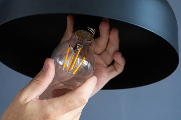 istock Close-up. A hand changes a light bulb in a stylish loft lamp. Spiral filament lamp. Modern interior decor. 1221970193