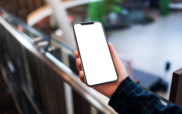istock a woman holding mobile phone with blank white screen indoors 1221970412