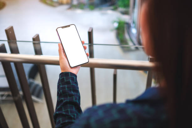 istock a woman holding mobile phone with blank white screen indoors 1221970418