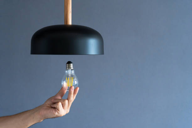 istock Close-up. A hand changes a light bulb in a stylish loft lamp. Spiral filament lamp. Modern interior decor. 1221970486