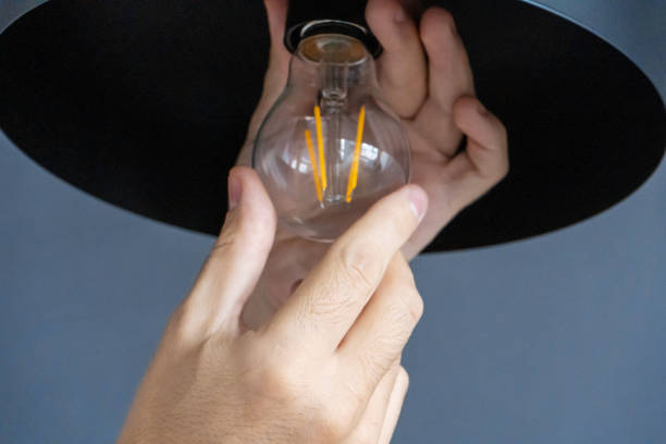 istock Close-up. A hand changes a light bulb in a stylish loft lamp. Spiral filament lamp. Modern interior decor. 1221970518