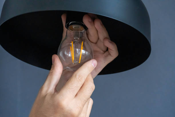 istock Close-up. A hand changes a light bulb in a stylish loft lamp. Spiral filament lamp. Modern interior decor. 1221970611