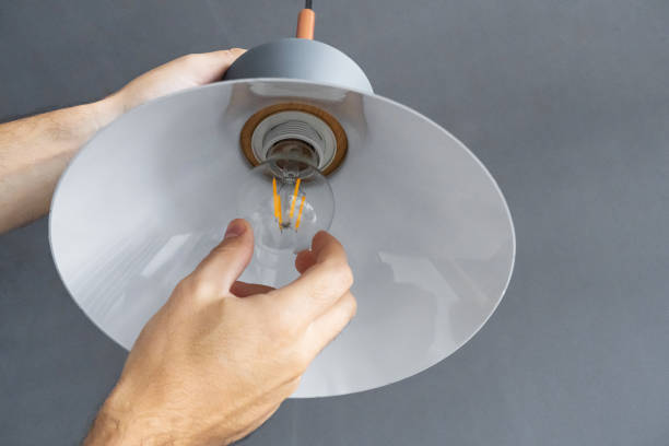 istock Close-up. A hand changes a light bulb in a stylish loft lamp. Spiral filament lamp. Modern interior decor. 1221970916