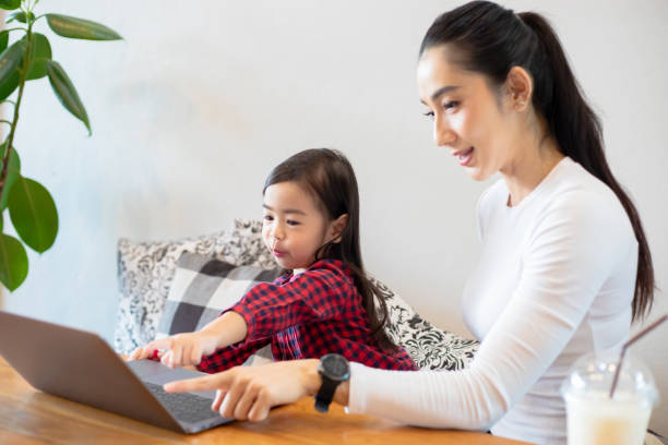 istock Asian mothers are teaching their daughters to read a book and use notebooks and technology for online learning during school holidays at home. Educational concepts and activities of the family 1221972256