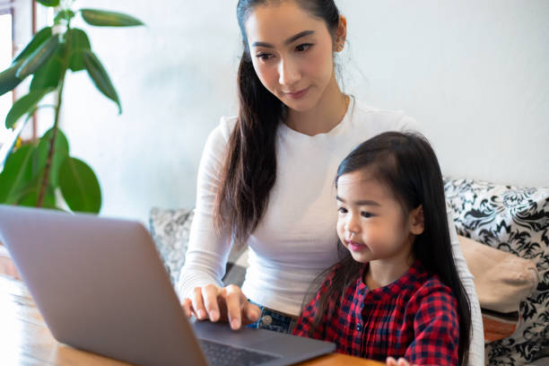 istock Asian mothers are teaching their daughters to read a book and use notebooks and technology for online learning during school holidays at home. Educational concepts and activities of the family 1221972279