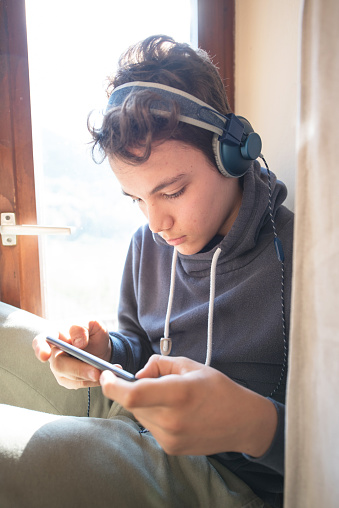 Teenage Boy with Headphones Listening to Music on a Smartphone