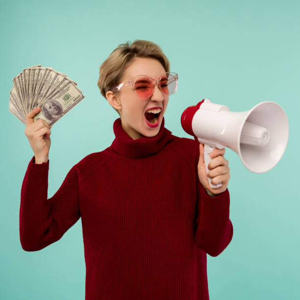 mujer joven con gafas de sol rosas con dinero gritando al altavoz - easy money audio fotografías e imágenes de stock