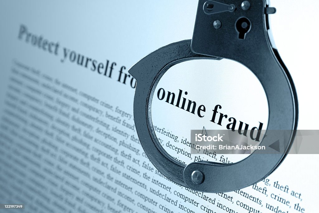 Online Fraud Pair of handcuffs frame the words online fraud on a computer monitor Computer Crime Stock Photo