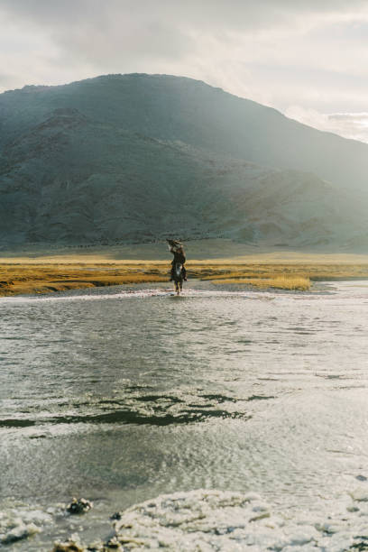 istock Eagle hunter on horse riding though  the river in Mongolia 1221974064