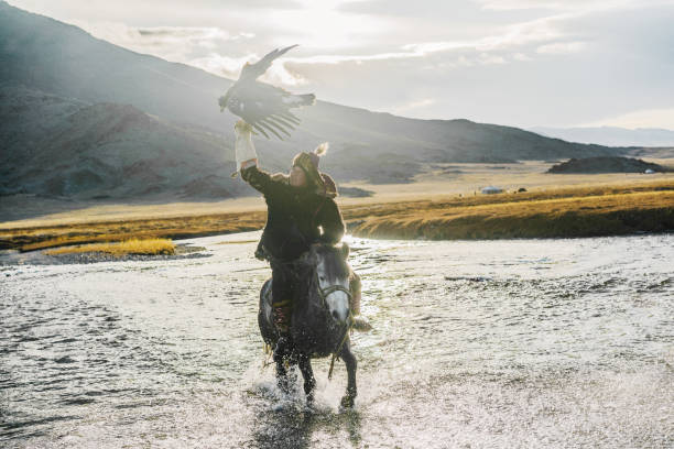 istock Eagle hunter on horse riding though  the river in Mongolia 1221974925