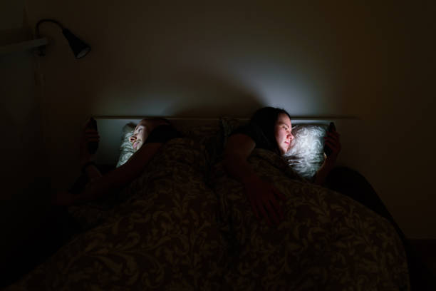 istock Couple using phones lying in bed before sleep 1221975104