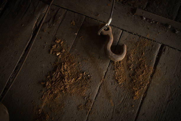 Rusty hook lying on an old dirty wooden floor stock photo
