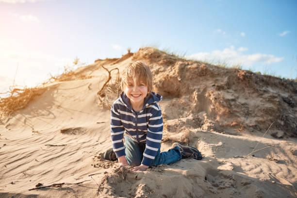 istock Happy boy jumping on sand at sunny day 1221978334