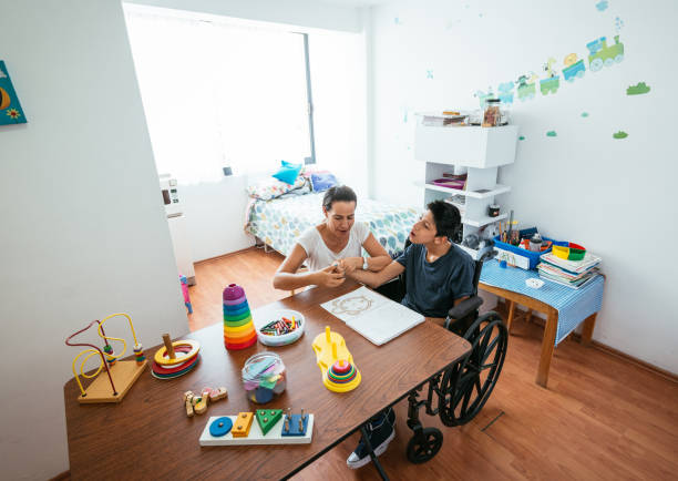 istock Mother teaching her son with cerebral palsy at home during coronavirus pandemic 1221978603