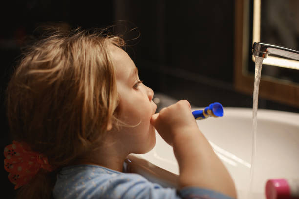 istock Little girl looking at herself in the mirror while washing her teeth before sleeping 1221978832