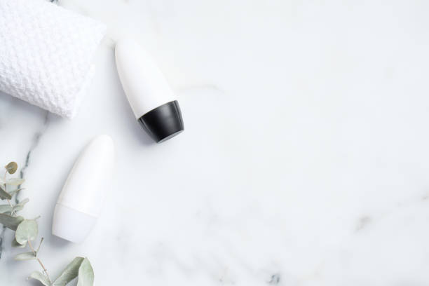 istock Roll-on deodorant packaging with eucalyptus leaf and towel on marble background. Flat lay, top view, copy space. Blank antiperspirant bottles mockups, sweat protection concept 1221981975