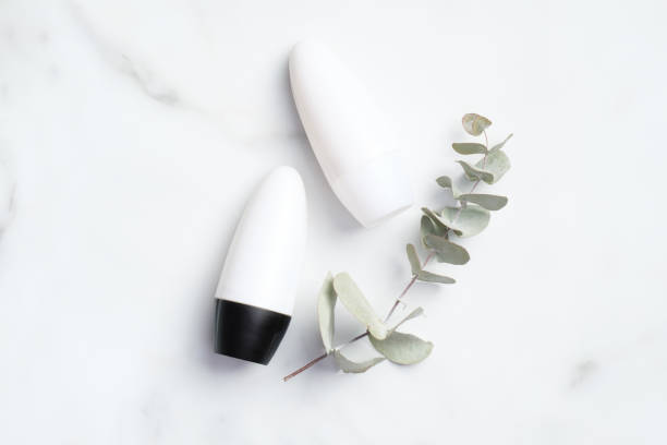 istock Roll-on deodorant bottles with eucalyptus leaf on marble background. Antiperspirant packaging mockup, sweat protection concept. Flat lay, top view 1221982001