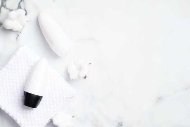 istock Deodorant bottles with cotton flowers on marble background. Flat lay, top view. White antiperspirant packaging, sweat protection product concept 1221982049