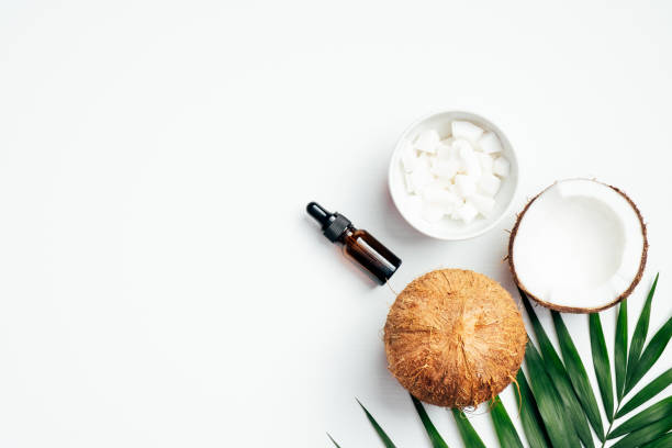 istock Coconut essential oil bottle with sliced coconut in bowl, tropical palm leaf, half of coconut on white background. Flat lay, top view. SPA natural organic cosmetic for skin care, body treatment 1221982976