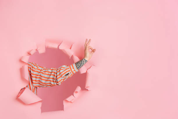 istock Male hand pointing, showing nice in torn coral paper hole background, copyspace 1221984634