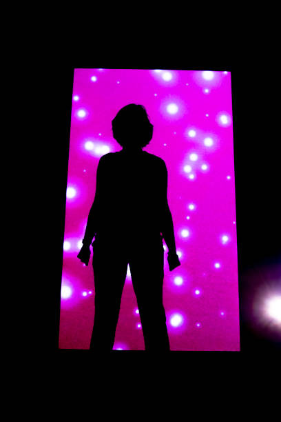 Woman Standing Against an Illuminated Pink Wal stock photo