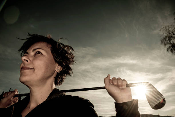 Golfer Leaning Her Golf Club on Her Shoulders with Sunlight stock photo