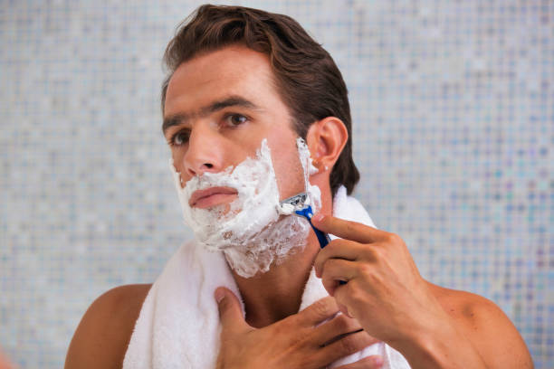 istock Portrait of young attractive man shaving his beard while looking in the mirror 1221987336