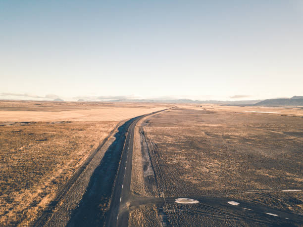 Dirt road forward throe volcanic landscape against clear blue sky. Iceland