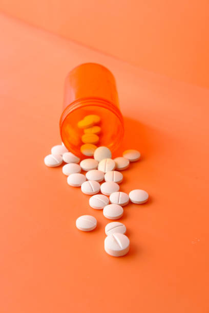 istock high angle view of white pills spilling on orange background 1221987669