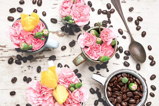 Coffee background. Coffee beans and pink flowers on retro table