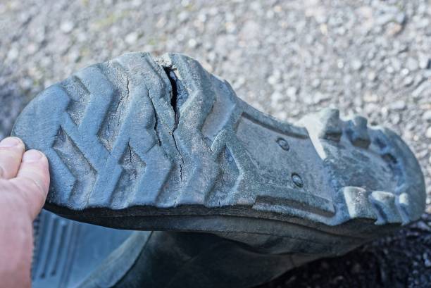 istock hand holds the sole with a crack and a hole on an old green rubber boot 1221989365