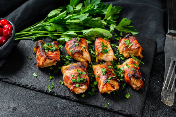 istock stuffed chicken breasts, fillets rolled in bacon. Black background. Top view 1221990465