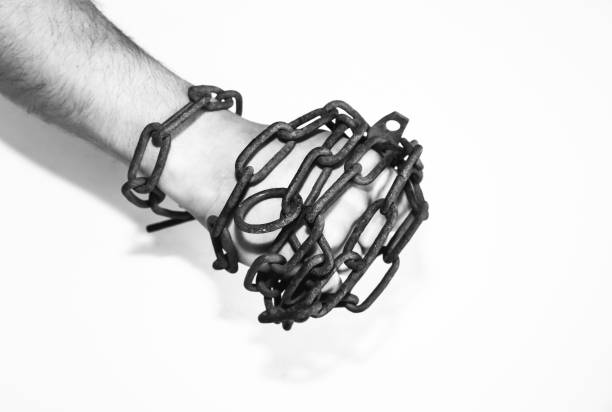 istock Hands in old rusty chains. Man in the trap. Slave concept. Isolated on white background. 1221990528