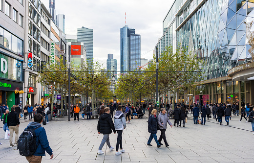 Frankfurt, Germany - Pedestrians on a busy central shopping street, with the office towers of Frankfurt's financial district on the horizon.