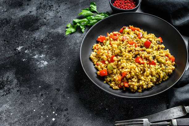 istock Bulgur with vegetables and meat on a plate. Black background. Top view. Copy space 1221992610