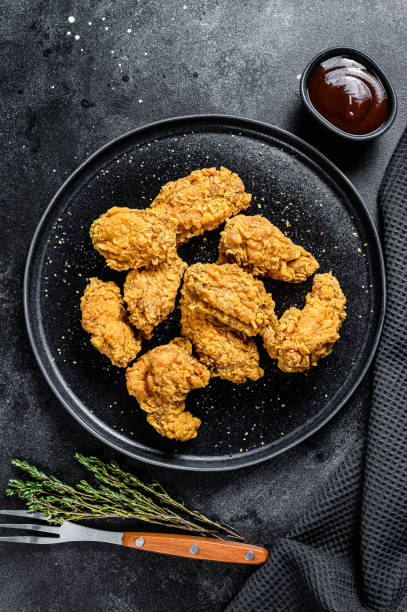 istock homemade baked crispy chicken wings.  Black background. Top view 1221993524