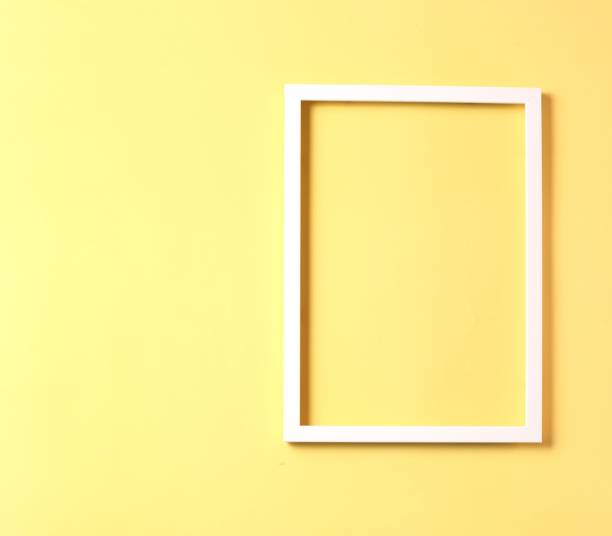 istock White photo frame on pastel yellow color 1221993715