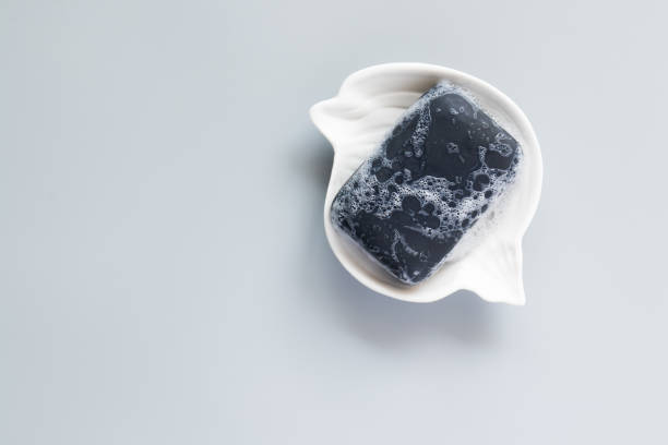 istock Black soap bar and foam in the soap dish on a grey background. Hand made soap. For protect, health. 1221993995