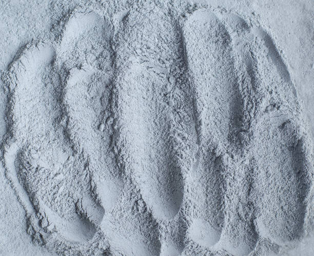 istock Gray bentonite facial clay powder (alginate mask, face cream, body wrap) texture close up, selective focus. Abstract background with strokes. 1221994529