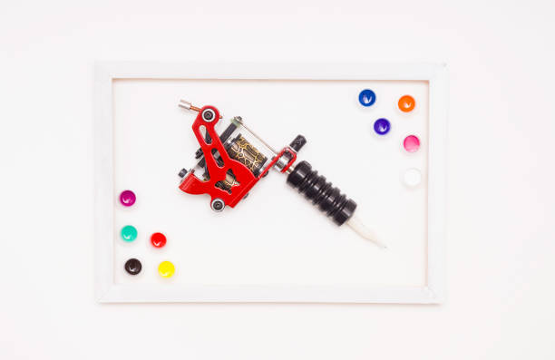 istock Tattoo machine on a white background, white frame, colored tattoo ink in plastic jars. The view from the top. 1221996857